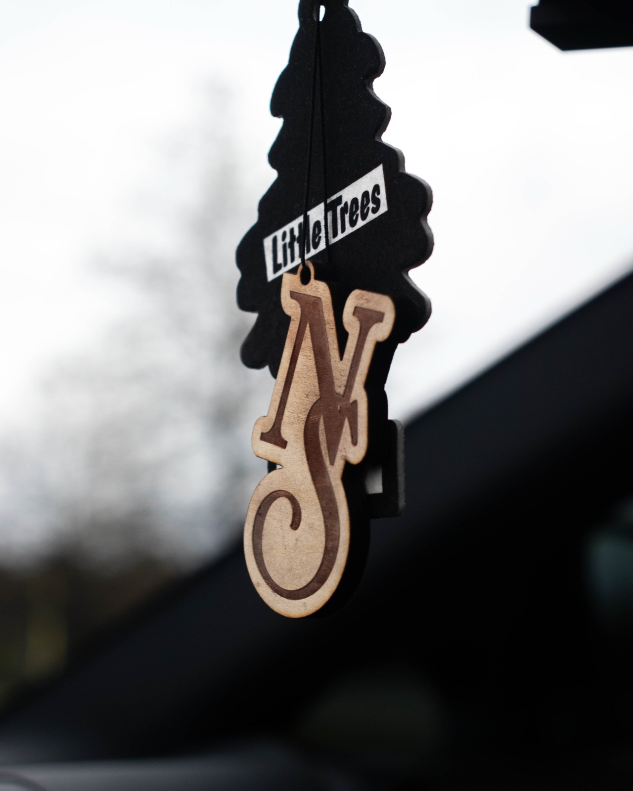 Engraved wood air freshener hanging from a mirror