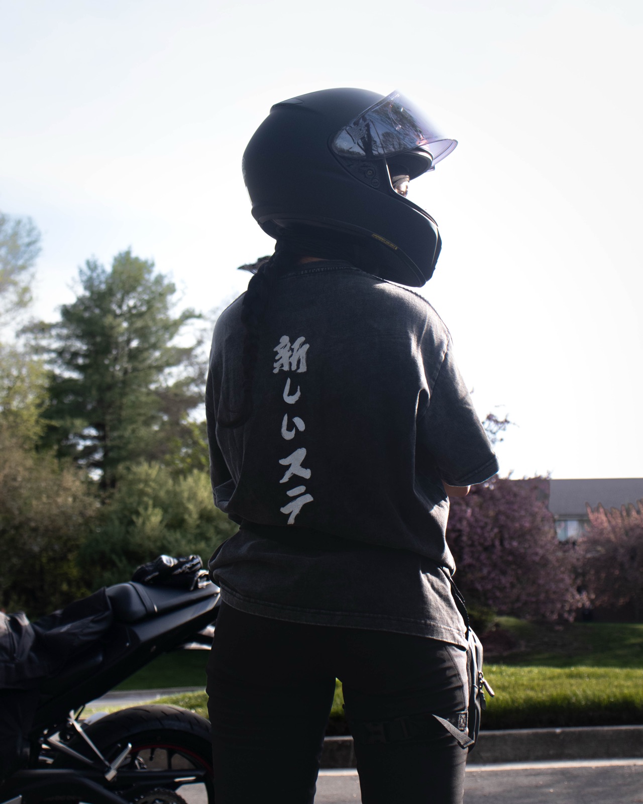 Rider in a New Stage tee beside a motorcycle