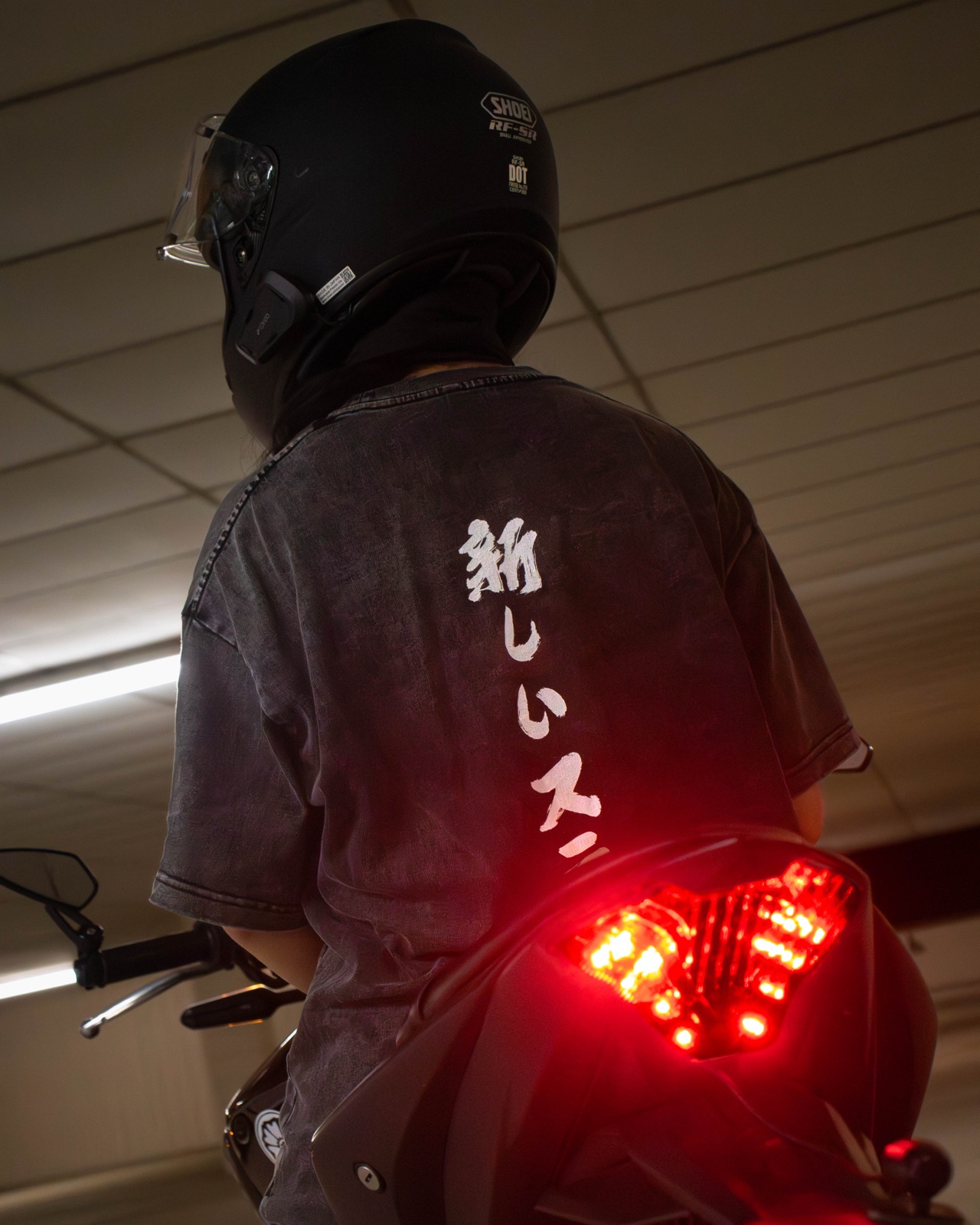 New Stage kanji tee on a motorcycle under garage light