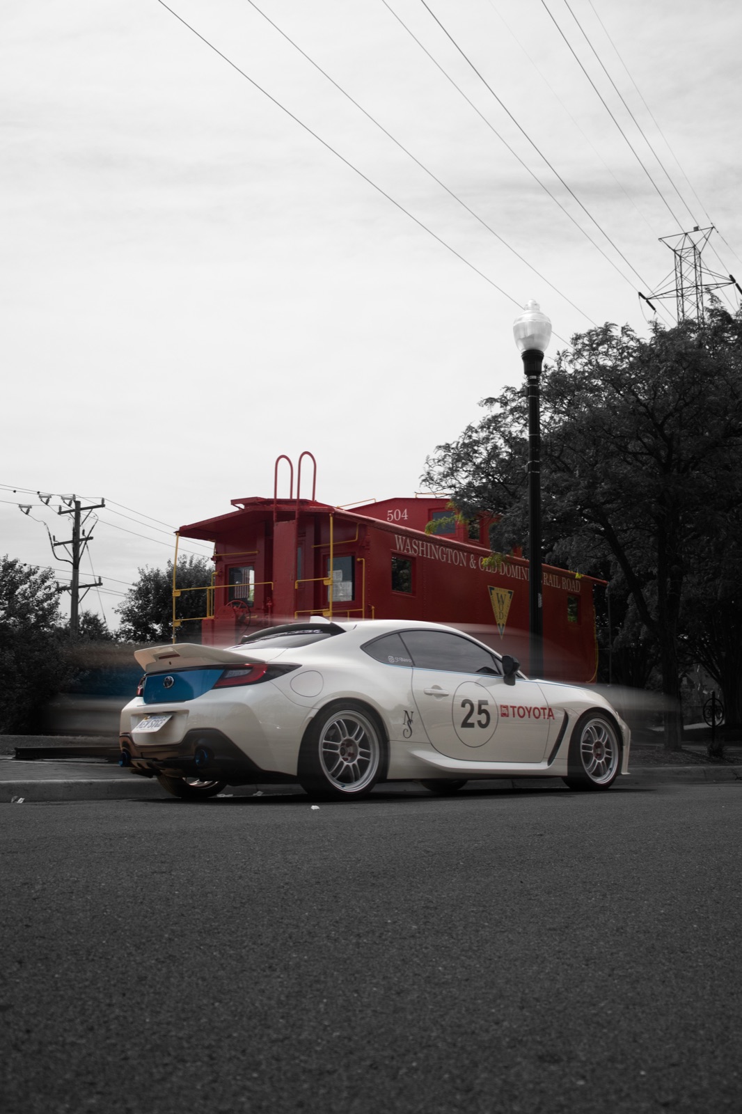 Selective-colour edit: white coupe against a red caboose